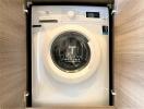 Modern built-in washing machine in a compact laundry room cabinet