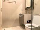 Modern bathroom interior with beige tiles, featuring a toilet, shower area, and washbasin with storage