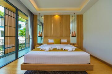 Modern bedroom with a king-sized bed, floor-to-ceiling windows, and elegant wooden accents
