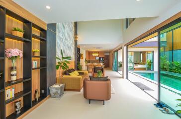 Spacious and tastefully designed living room with glass wall overlooking the pool