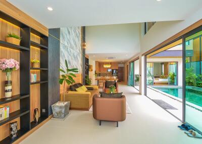 Spacious and tastefully designed living room with glass wall overlooking the pool
