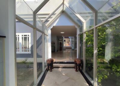 Bright and spacious sunroom leading to the main house with glass walls and ceiling