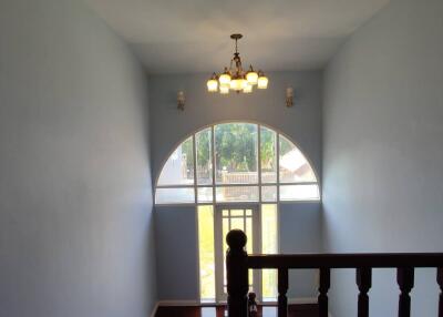 Elegant staircase landing with arched window and chandelier