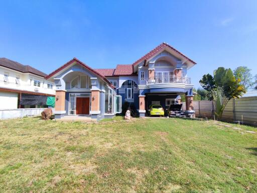 Spacious suburban home with a large front yard and multiple parked cars