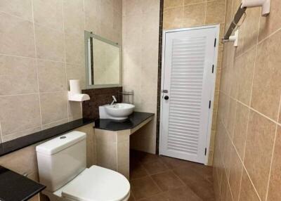 Modern bathroom with tiled floors and walls featuring sink, toilet, and door