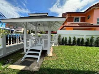 Cozy white gazebo with seating in a vibrant garden