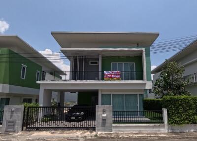 Two-story house with a for sale sign, surrounded by green painted walls, under a blue sky