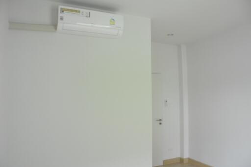 Minimalist bedroom with air conditioning unit and wooden flooring