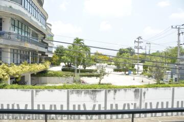 Exterior view of a modern building with lush greenery and parking area