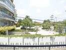 Exterior view of a modern building with lush greenery and parking area