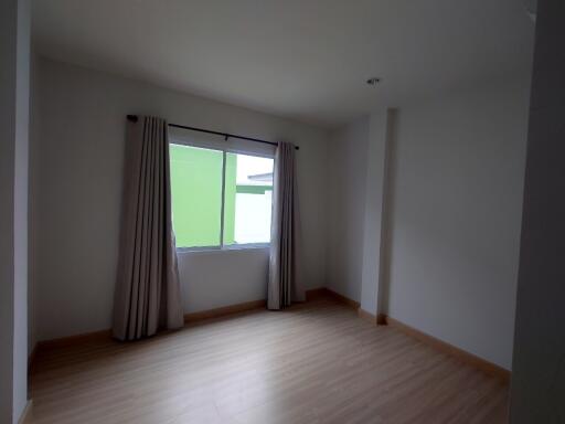 Spacious and empty living room with large windows and wooden flooring