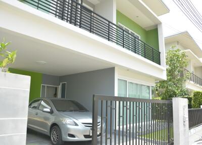 modern house with green walls and a balcony over a carport