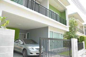 modern house with green walls and a balcony over a carport
