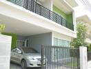 modern house with green walls and a balcony over a carport