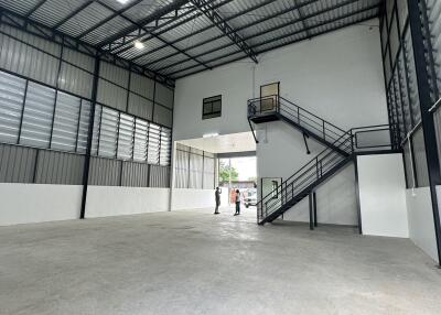 Spacious industrial warehouse interior with metal staircase and high ceiling