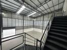 Spacious industrial warehouse interior with overhead lighting and mezzanine area