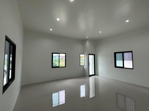 Spacious and bright modern living room with large windows and glossy tiled floor