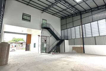 Spacious industrial building with large open area, mezzanine floor, and staircase