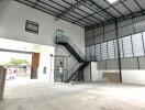 Spacious industrial building with large open area, mezzanine floor, and staircase
