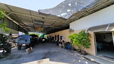 Wide angle view of a spacious covered outdoor garage with multiple vehicles and a seating area