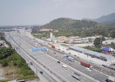 Aerial view of a busy highway with surrounding commercial areas and lush green mountains in the background