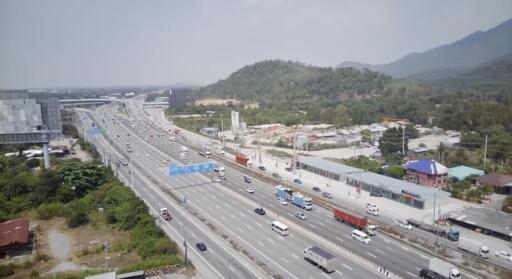 Aerial view of a busy highway with surrounding commercial areas and lush green mountains in the background
