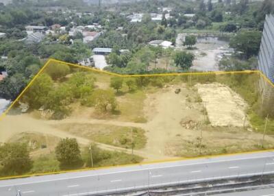Aerial view of a vacant land plot outlined in yellow near urban area