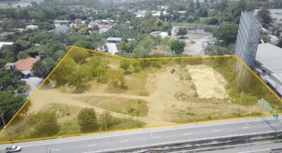 Aerial view of a vacant land plot outlined in yellow near urban area