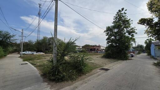 Suburban street view with visible power lines and scattered vegetation