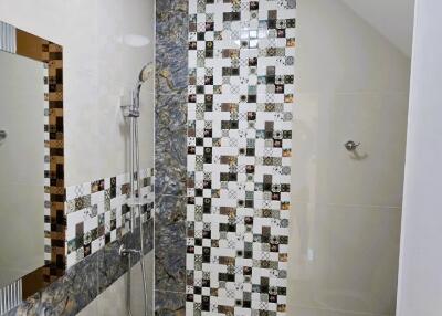 Modern bathroom with decorative tiled shower, white sink, and toilet