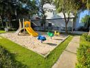 Spacious backyard with children's play area featuring swings and slides