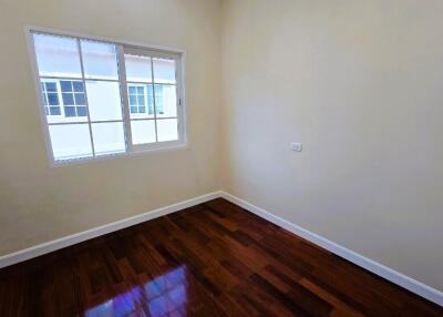 Empty bedroom with polished wooden floor and large window