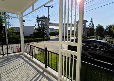 Spacious front porch of a modern residence with a view of the driveway and surrounding gated community