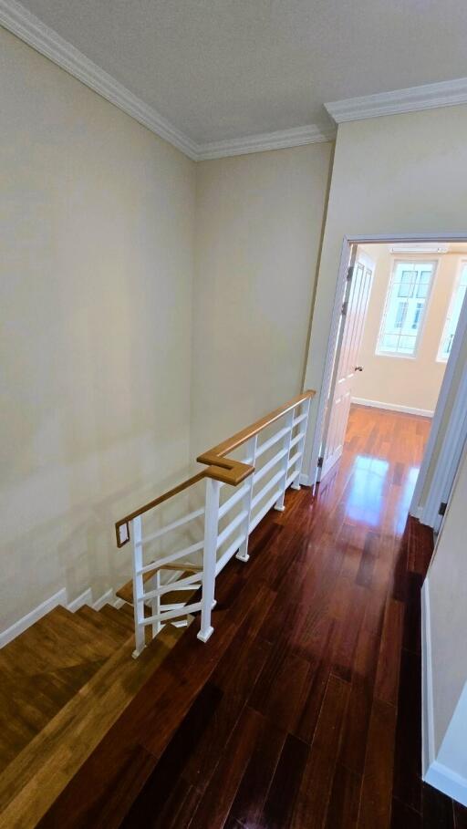 Bright and spacious hallway with wooden flooring and light walls