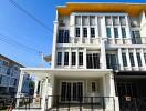 Modern three-story residential building with bright blue sky