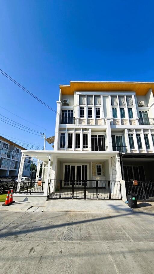 Modern three-story residential building with bright blue sky