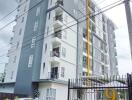 Modern high-rise residential building with balconies and a gated entrance