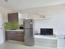 Modern kitchen with integrated living space featuring stainless steel refrigerator and flat-screen TV