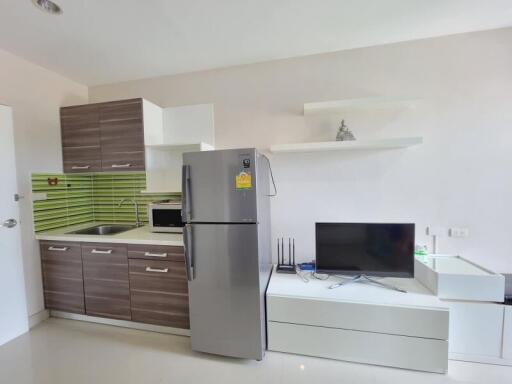Modern kitchen with integrated living space featuring stainless steel refrigerator and flat-screen TV
