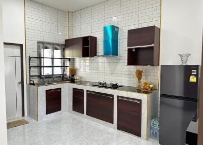 Modern kitchen interior with white tiled walls, wooden cabinets, and stainless steel appliances