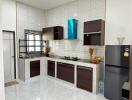 Modern kitchen interior with white tiled walls, wooden cabinets, and stainless steel appliances