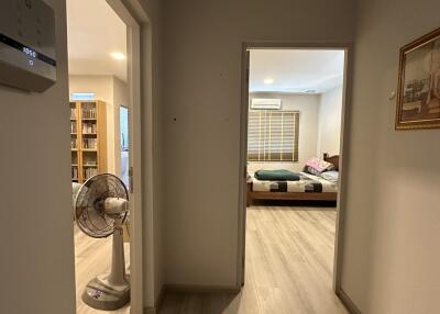 View through a well-lit hallway into a tidy bedroom with modern decor