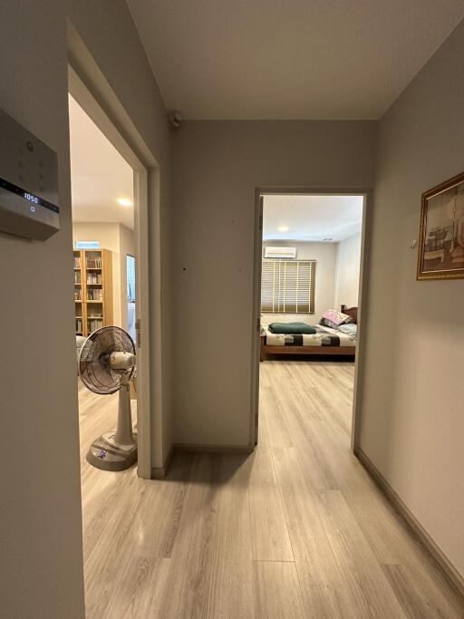 View through a well-lit hallway into a tidy bedroom with modern decor