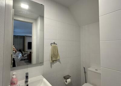 Neat bathroom with white tiles, sink, toilet, and mirrored medicine cabinet