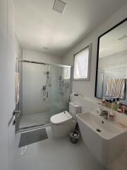 Modern spacious bathroom with glass shower enclosure and bright lighting