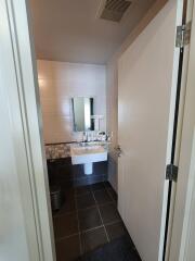 Interior view of a clean and modern bathroom with a white sink, mirror, and tiled floor