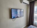 Modern bedroom with wall-mounted television and air conditioning unit