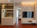 Modern compact living area with an integrated kitchen, workspace, and bedroom view