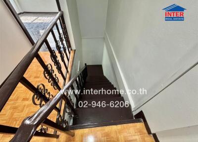 Interior staircase with wooden floors and black metal railing