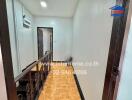 Brightly lit hallway with parquet flooring and white walls